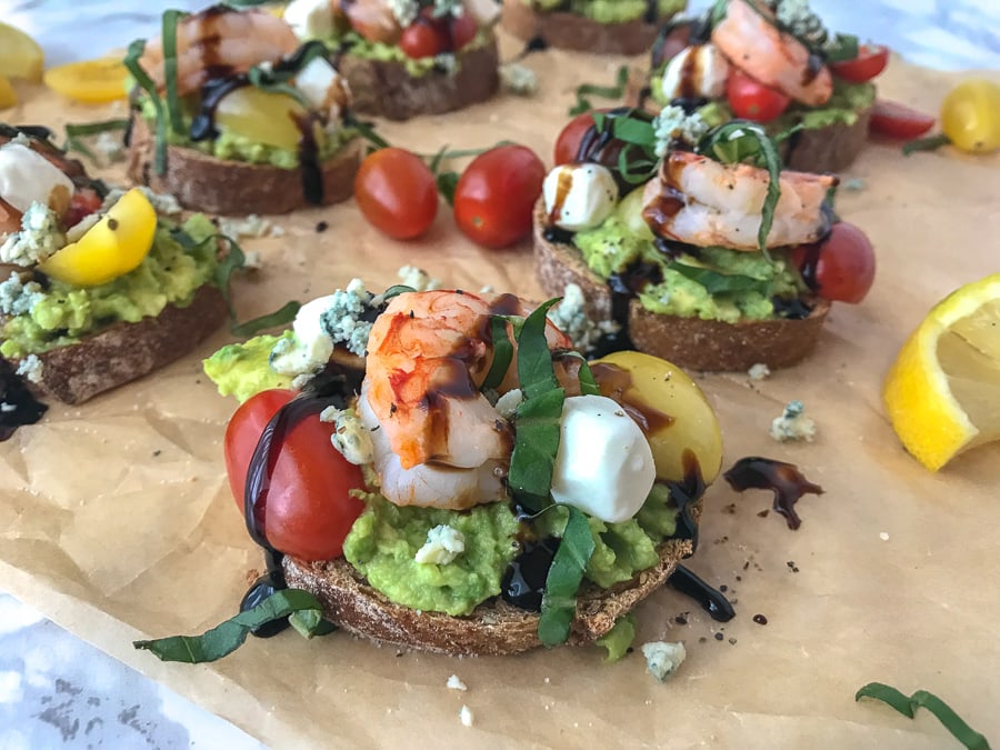 This Lemon Shrimp and Avocado Caprese is made with fresh mozzarella cheese, avocado, basil, blue cheese, heirloom tomato medley, and wild caught shrimp. Full of flavor, absolutely refreshing and only 202 calories per slice. #shrimp #lemonshrimp #caprese #avocado #capresetoast #healthy | https://withpeanutbutterontop.com