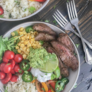 Steak Fajita Bowls with Garlic Lime Cauliflower Rice - these fajita bowls will complete your Taco Tuesday cravings! The steak is marinated in a garlic lime sauce and is super tender, as well as flavorful. #bowls #healthy #steakfajitas #fajitas | www.withpeanutbutterontop.com