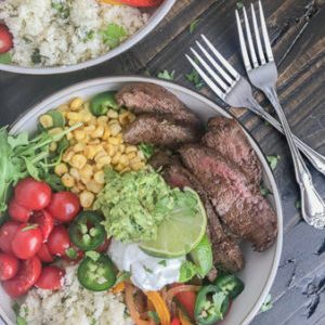 Steak Fajita Bowls with Garlic Lime Cauliflower Rice - these fajita bowls will complete your Taco Tuesday cravings! The steak is marinated in a garlic lime sauce and is super tender, as well as flavorful. #bowls #healthy #steakfajitas #fajitas | www.withpeanutbutterontop.com