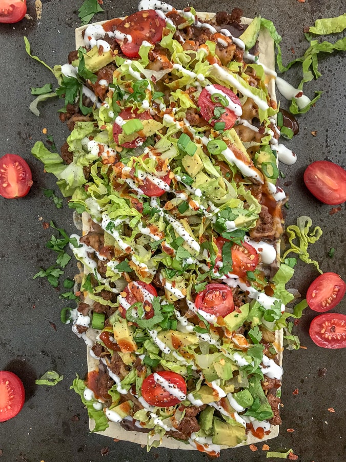 Loaded Skinny Taco Flatbread Pizza - a healthier, lower-carb version of our favorite pizza! Loaded with toppings, easy and quick to make! #pizza #tacos #tacopizza #tacotuesday | https://withpeanutbutterontop.com