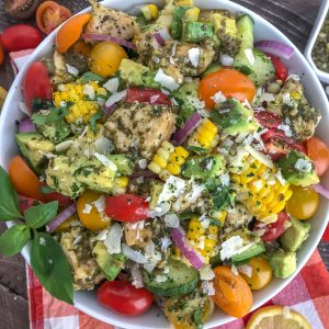 This healthy, super simple to make, and delicious Lemon Pesto Chicken Avocado Salad recipe is loaded with avocado, cherry tomatoes, red onions, corn, and the most delicious lemon pesto chicken. #healthy #pestochicken #salad | https://withpeanutbutterontop.com