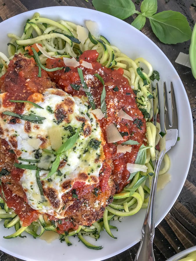 incredibly delicious chicken that is super tender on the inside, yet crispy on the outside. Served over cooked zucchini noodles to make for a lower-carb, light and healthy meal. #chickenparmesan #zoodles #healthy #lowcarb | https://withpeanutbutterontop.com