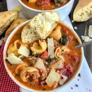 One Pot Sausage Tortellini Tomato Soup - a super delicious and easy recipe that is filled with turkey sausage, cheese tortellini, kale, and herbs in a delicious tomato base! Hearty, filling, and yummy! #soup #healthysoup #sausagetortellinisoup | https://withpeanutbutterontop.com