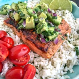 Super simple, quick and healthy recipe! Perfectly seasoned and pan seared salmon over a bed of cilantro lime rice and garnished with a creamy avocado salsa that is bursting full of flavor! #cajunsalmon #salmon #searedsalmon #salmonbowl | https://withpeanutbutterontop.com