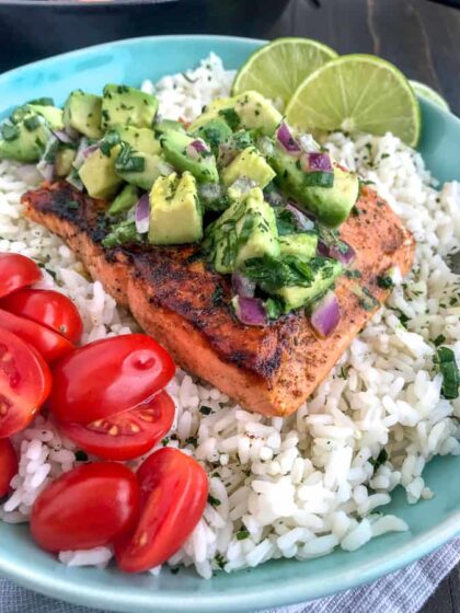 Super simple, quick and healthy recipe! Perfectly seasoned and pan seared salmon over a bed of cilantro lime rice and garnished with a creamy avocado salsa that is bursting full of flavor! #cajunsalmon #salmon #searedsalmon #salmonbowl | https://withpeanutbutterontop.com