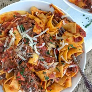 Fall apart tender, shredded beef in a rich, fire-roasted tomato sauce that is tossed with pappardelle pasta and topped with freshly grated parmesan cheese. The ultimate comfort dish made easily in your Instant Pot! #ragu #pappardelle #instantpot #comfortfood #easyrecipes | https://withpeanutbutterontop.com