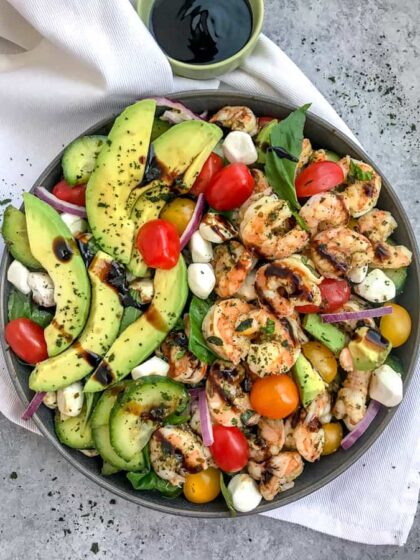 A light, refreshing salad that is perfect for any occasion. Loaded with fresh mozzarella, basil leaves, avocado slices, cherry tomatoes, cucumbers and tender shrimp - all tossed in a sweet balsamic glaze. Easy and bursting full of summertime flavors! #capresesalad #salad #shrimpsalad #summersalads | https://withpeanutbutterontop.com