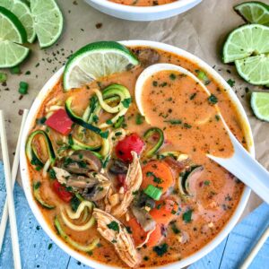 Learn how to make Thai easily and quickly at home with this ONE POT Thai Red Curry Chicken Zoodle Soup recipe! So much better than any takeout and you can control exactly what goes in it. Layers upon layers of delicious vegetables, spiralized zucchini, and tender, shredded chunks of chicken, all in a coconut red curry broth. Absolutely outstanding and delicious! #thai #takeout #lowcarb #soup | https://withpeanutbutterontop.com