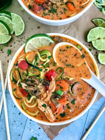 Learn how to make Thai easily and quickly at home with this ONE POT Thai Red Curry Chicken Zoodle Soup recipe! So much better than any takeout and you can control exactly what goes in it. Layers upon layers of delicious vegetables, spiralized zucchini, and tender, shredded chunks of chicken, all in a coconut red curry broth. Absolutely outstanding and delicious! #thai #takeout #lowcarb #soup | https://withpeanutbutterontop.com