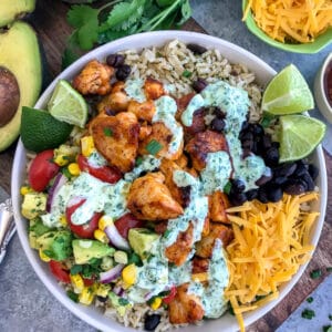 Tender, juicy chicken, Avocado Corn Salsa, and black beans served over brown rice and drizzled in Creamy Cilantro Lime Sauce. So much flavor you will forget that you're eating healthy! #tacotuesday #tacos #tacobowl #healthy | https://withpeanutbutterontop.com