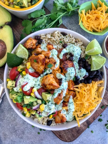 Tender, juicy chicken, Avocado Corn Salsa, and black beans served over brown rice and drizzled in Creamy Cilantro Lime Sauce. So much flavor you will forget that you're eating healthy! #tacotuesday #tacos #tacobowl #healthy | https://withpeanutbutterontop.com