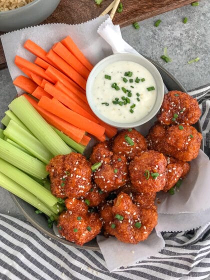 Cauliflower florets battered and baked until super crispy and then tossed in the an incredible sweet and spicy sauce. Sticky, crispy and so easy to make, you’ll be throwing your takeout menus away! #firecracker #firecrackercauliflower #cauliflower #takeout | https://withpeanutbutterontop.com