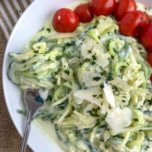 A light, fresh and easy dinner that will curb any creamy pasta craving! Cooked, tender zucchini noodles tossed in a creamy, garlic parmesan ricotta sauce and served with a side of blistered cherry tomatoes. The perfect healthy dinner option! #zoodles #parmesanzoodles | https://withpeanutbutterontop.com
