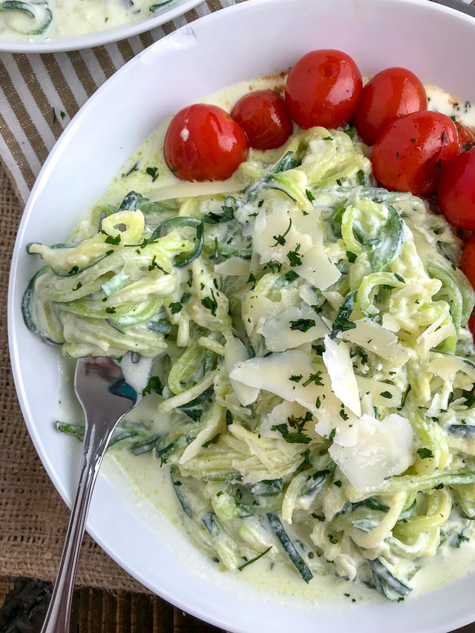 A light, fresh and easy dinner that will curb any creamy pasta craving! Cooked, tender zucchini noodles tossed in a creamy, garlic parmesan ricotta sauce and served with a side of blistered cherry tomatoes. The perfect healthy dinner option! #zoodles #parmesanzoodles | https://withpeanutbutterontop.com