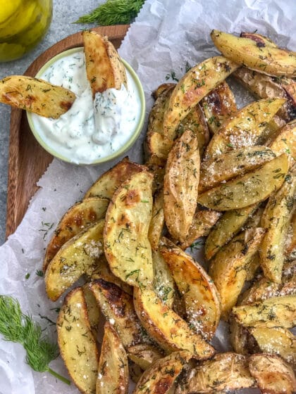 Calling all dill pickle lovers! These potato wedges are crispy on the outside, while being tender and flaky on the inside, with a hint of delicious dill pickle flavoring! The perfect appetizer or side dish to grilled chicken or burgers! #dillpickle #potatowedges #appetizer | https://withpeanutbutterontop.com