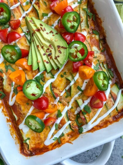 Creamy, shredded chicken stuffed into zucchini "rolls" and then baked in enchilada sauce and cheddar and monetary jack cheese. Very easy to make, low-carb, keto-friendly, and full of amazing flavors! #chickenenchiladas #lowcarb #keto #enchiladas | https://withpeanutbutterontop.com