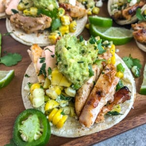 Easy, delicious grilled chicken tacos that are loaded with mexican street corn, mashed avocado, and creamy sriracha sauce!