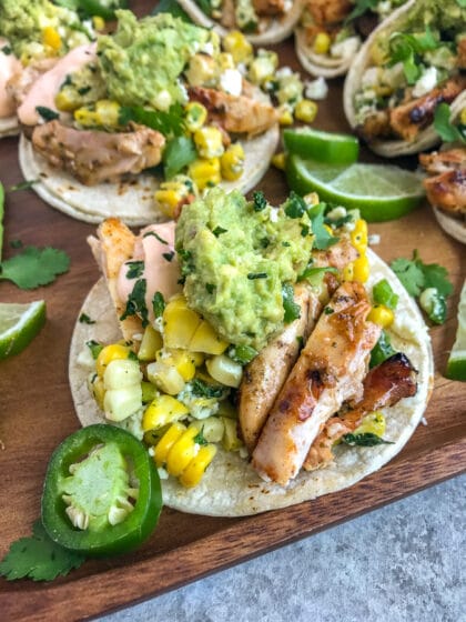 Easy, delicious grilled chicken tacos that are loaded with mexican street corn, mashed avocado, and creamy sriracha sauce!
