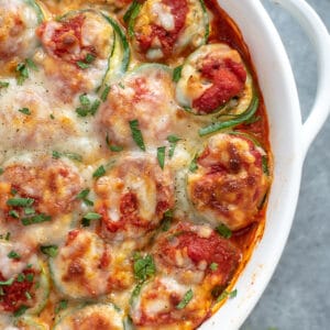 Baking dish filled with zucchini lasagna roll ups. Garnished with cheese and fresh seasonings. A great low-carb, gluten-free and healthy option to traditional lasagna.