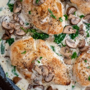 Cast iron skillet filled with a Creamy Mushroom and Spinach Chicken dish.