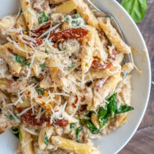 Bowl filled with creamy pasta, spinach, sun dried tomatoes, and turkey sausage.