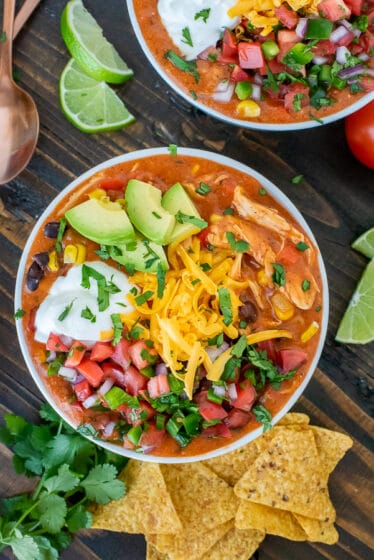 Bowl filled with chicken enchilada soup and garnished with avocado, greek yogurt, cheddar cheese and pico de gallo.