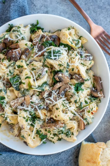Pan filled with creamy pasta, mushrooms, and spinach.