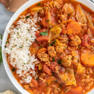 White bowl filled with cabbage roll soup, garnished with white rice.