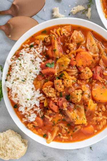 White bowl filled with cabbage roll soup, garnished with white rice.