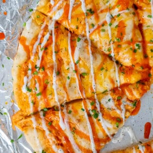 Buffalo Ranch Chicken Pizza sliced and garnished with buffalo sauce, ranch dressing and chopped chives.